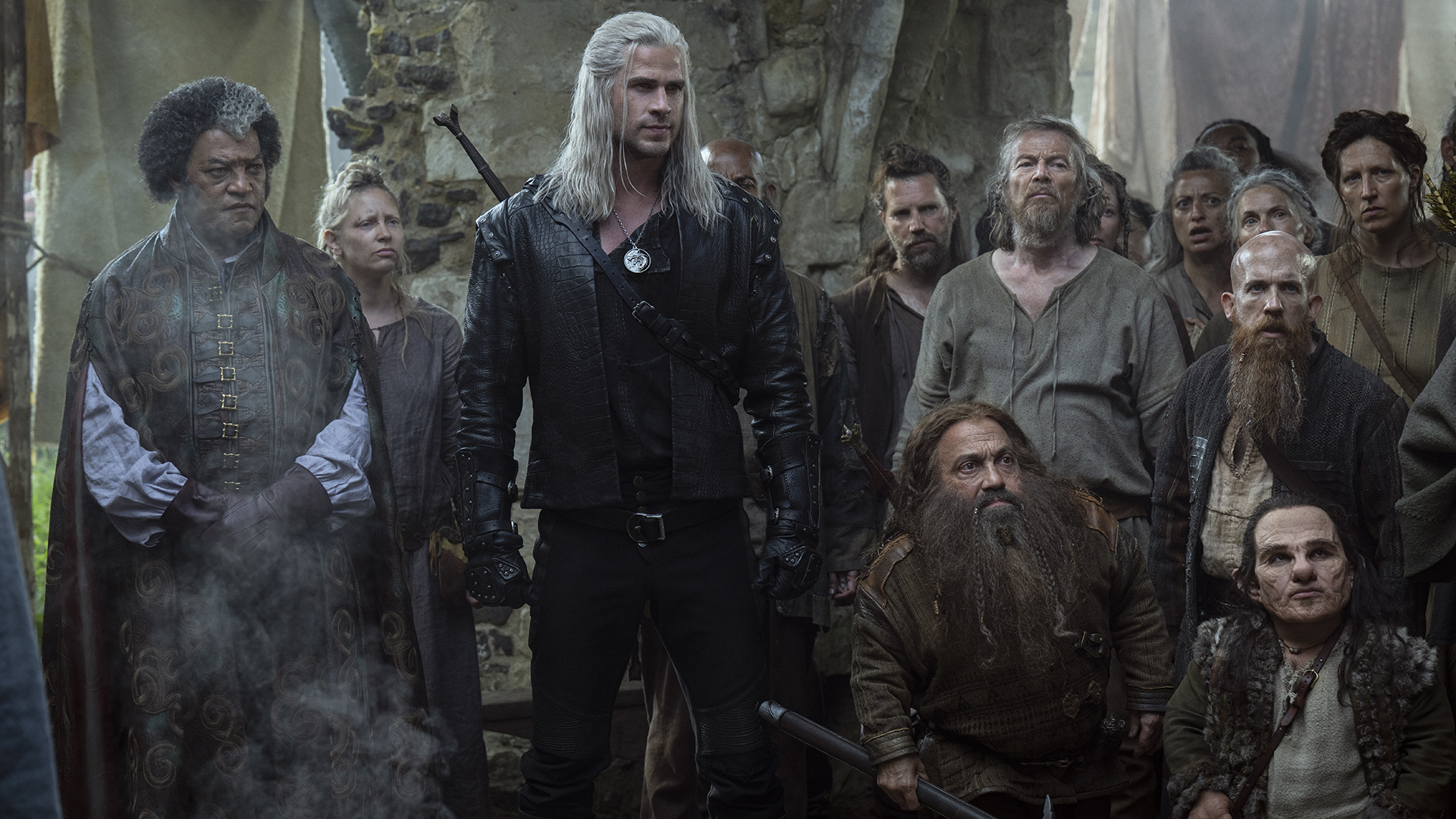 Regis and Geralt standing with some people and dwarves in The Witcher season 4