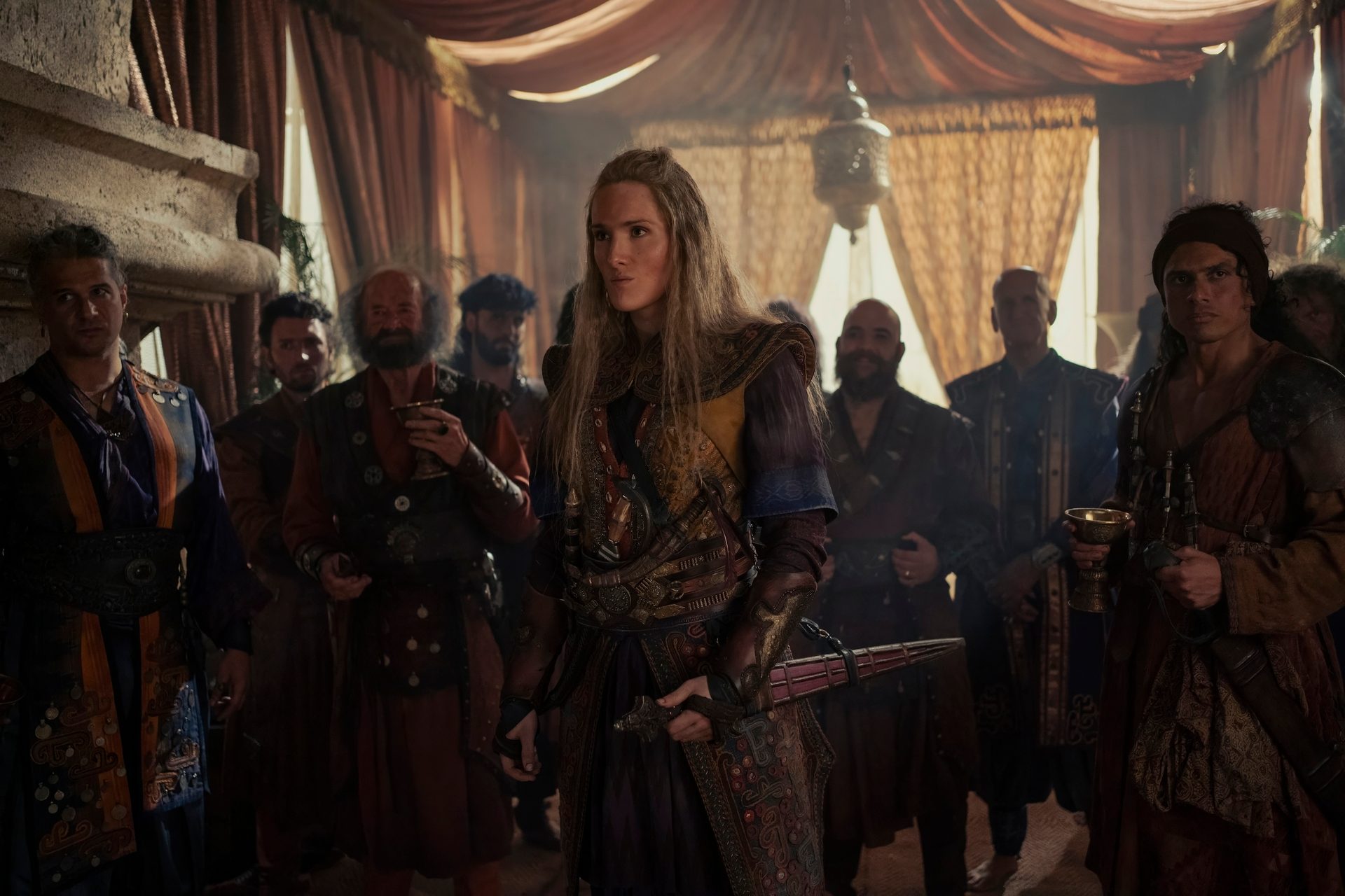 Abigail Thorn as Admiral Lohar in House of the Dragon stands in a crowded tent structure.