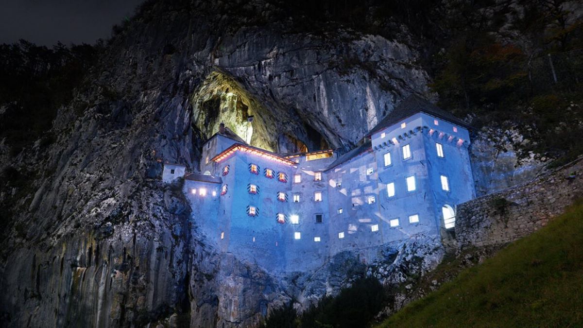Predjama Castle in Slovenia lit up at night.