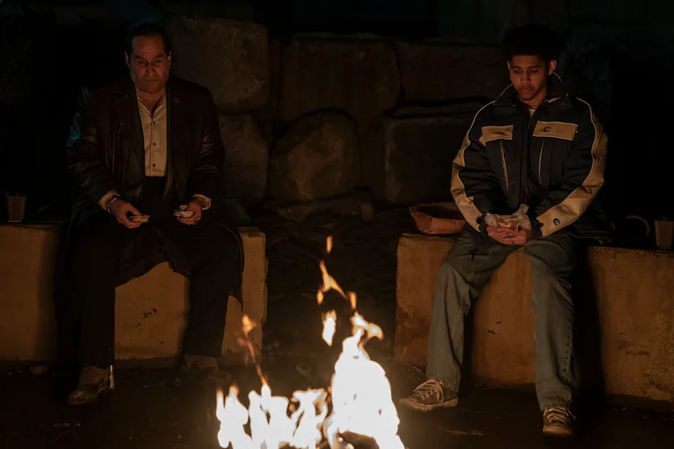 Oz Cobb (Colin Farrell) and Victor Aguilar (Rhenzy Feliz) sit and burn trash.